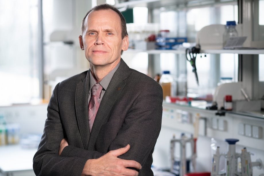 Herr Stahmann, Stellvertreter des Fajultätsrates, trägt ein braunes Hemd, sowie ein braunes Jacket mit einer rötlichen Krawatte. Herr Stahmann schaut mit verschänkten Armen und einem Lächeln dirket in die Kamera.