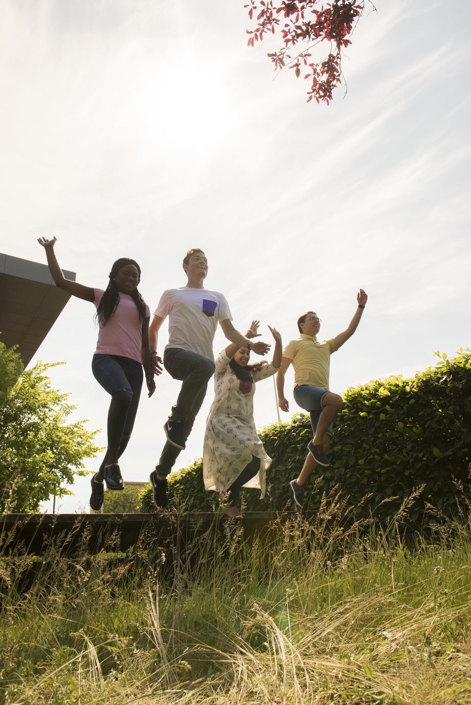 internationale Studierende springen am Campus im Sommer