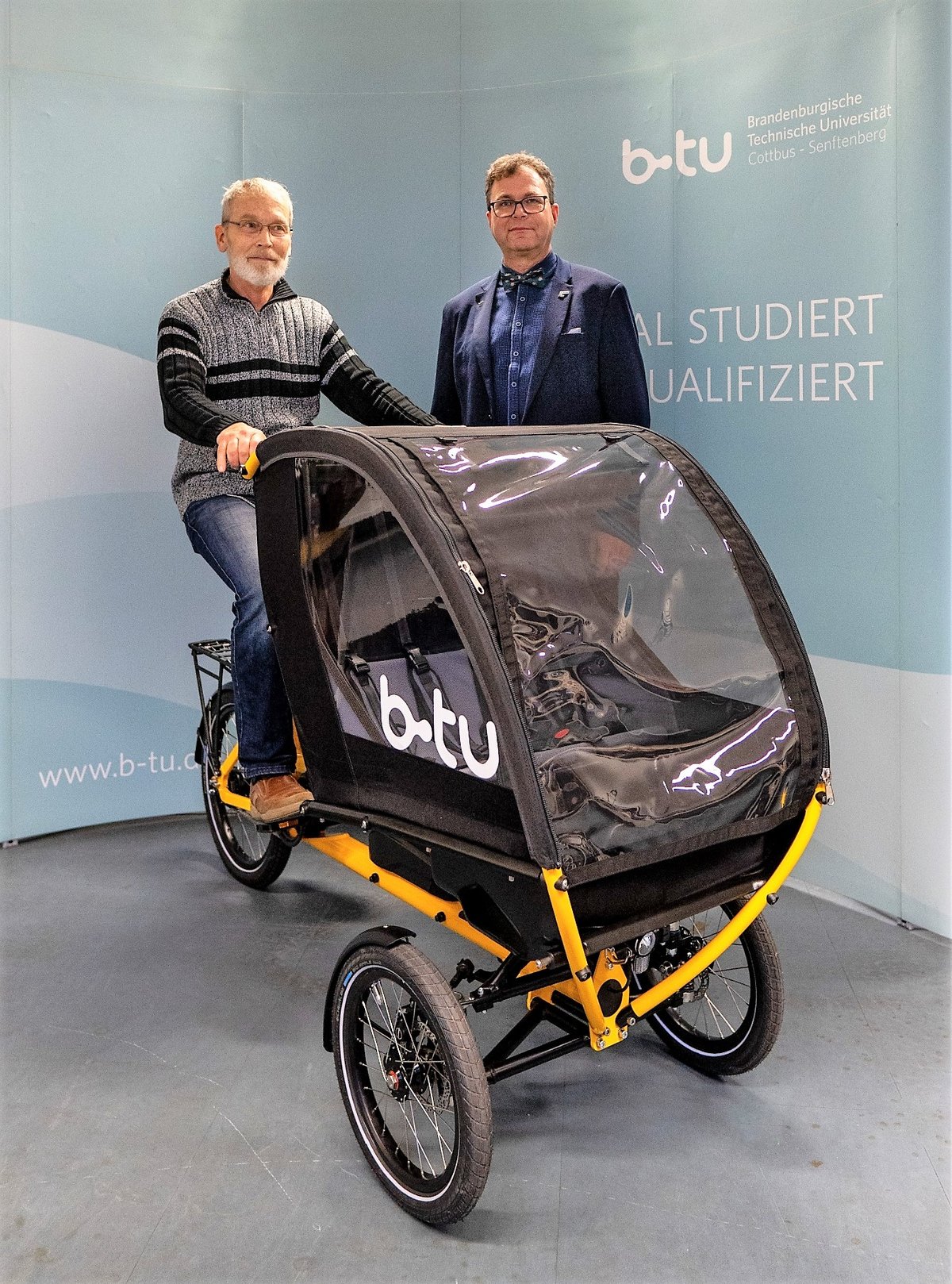 Prof. Dr. Thomas Meißner (sitzend) und Prof. Dr. Sylvio Simon (stehend) mit einem der beiden durch das IURS beschafften neuen Elektro-Lastenräder. Foto: Michael Weist