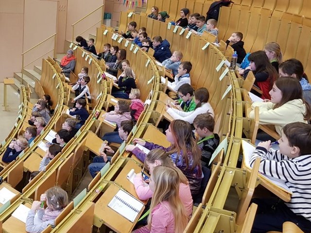 Mädchen und JUngen der Kinderuni sitzen im Hörsaal und folgen einer Vorlesung. Foto: Mark Nielson