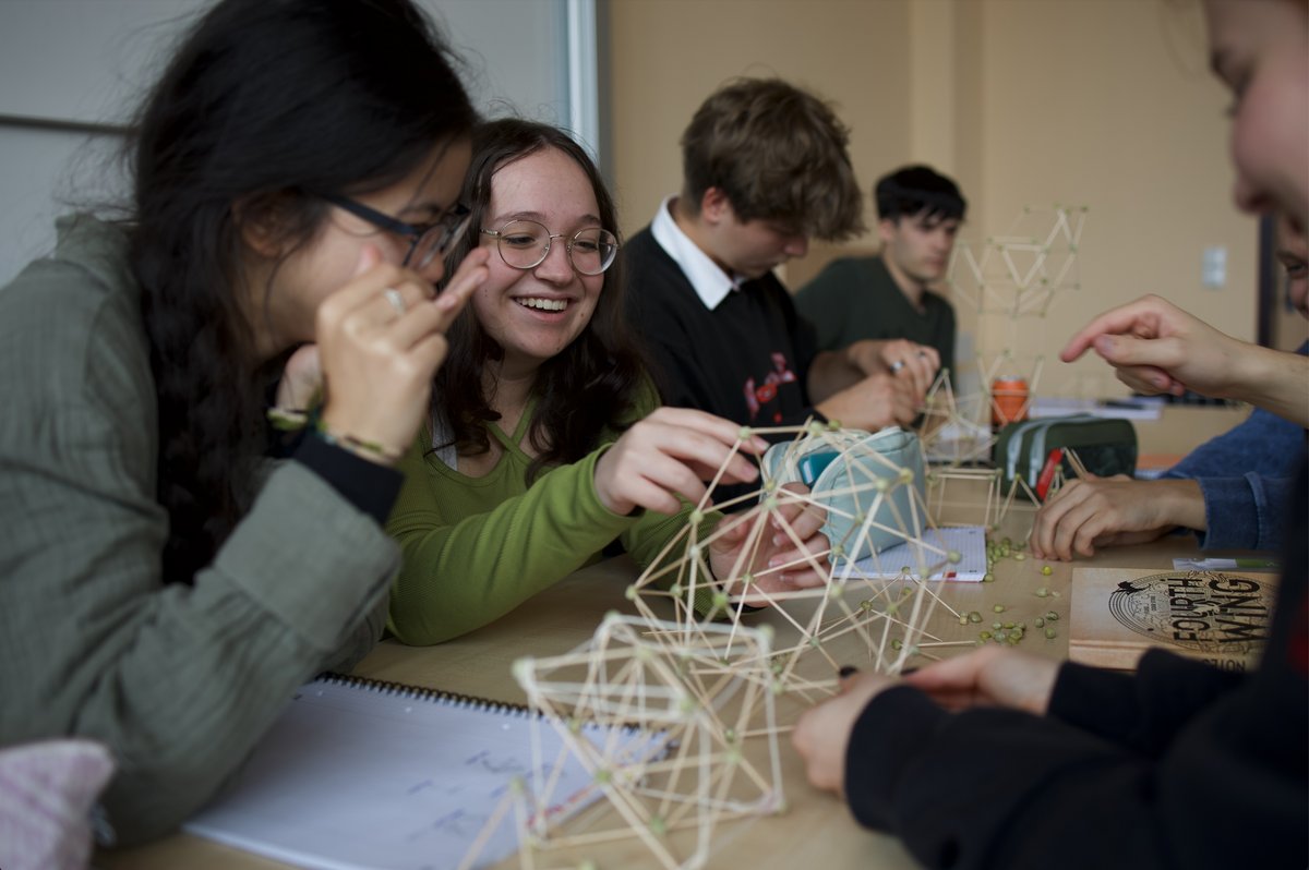 5 Studierende sitzen am Tisch und bauen mathematische Modelle aus Zahnstochern und Erbsen