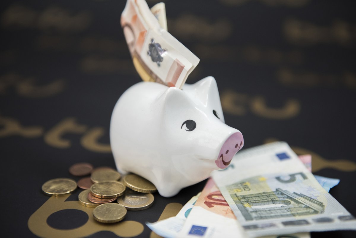 Ein Sparschwein mit Geldscheinen, die im Eingabeschlitz stecken.