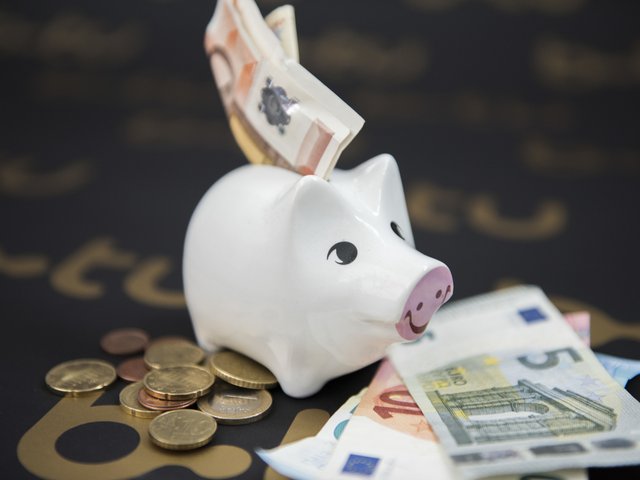 Ein Sparschwein mit Geldscheinen, die im Eingabeschlitz stecken.