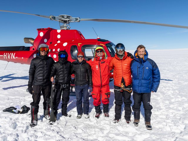 Gruppenbild mit Hubschrauber im Hintergrund
