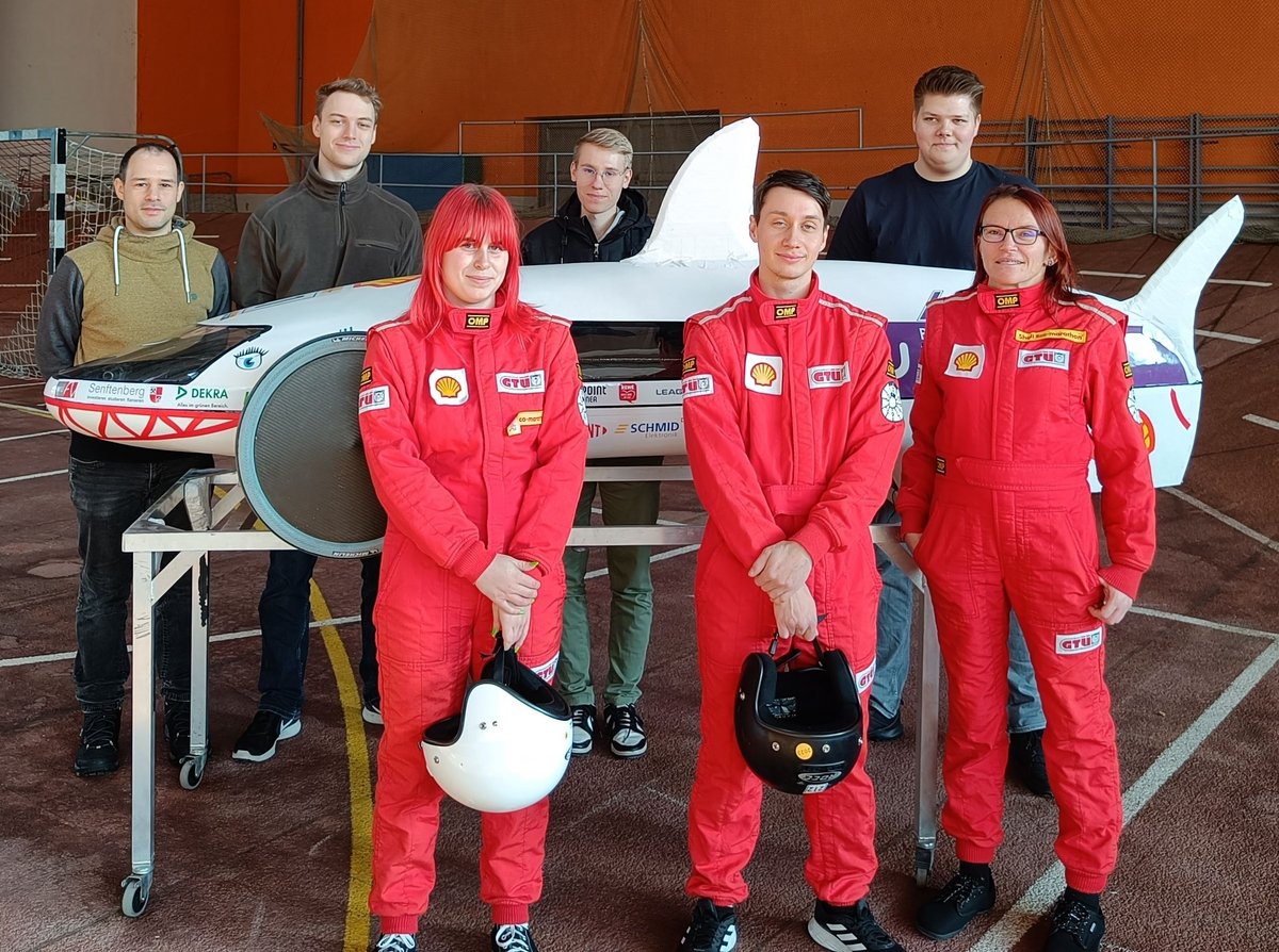 Members of the Lausitz Dynamics team in front of and behind their energy-saving vehicle.