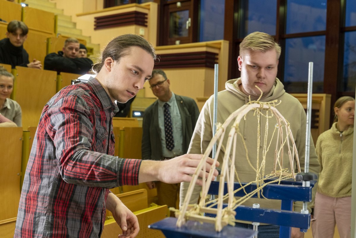 Two people clamp a bridge model into the test stand.