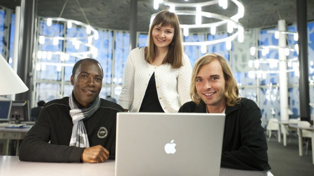 Drei junge Menschen sitzen an einem Laptop