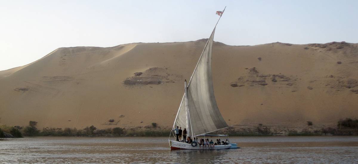 Ein Segelboot mit Studierenden des Masterstudiengangs Heritage Conservation and Site Management vor einer mit Sand überdeckten Steilküste