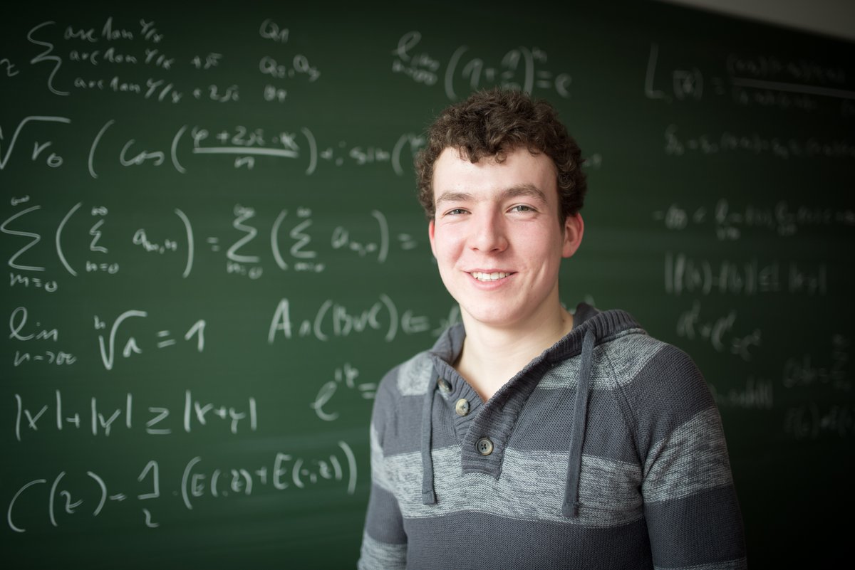 Mathematik-Student steht vor einer Tafel mit Formeln
