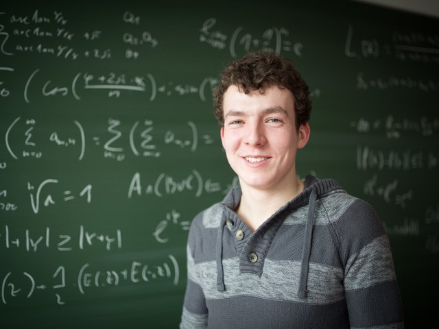 Mathematik-Student steht vor einer Tafel mit Formeln