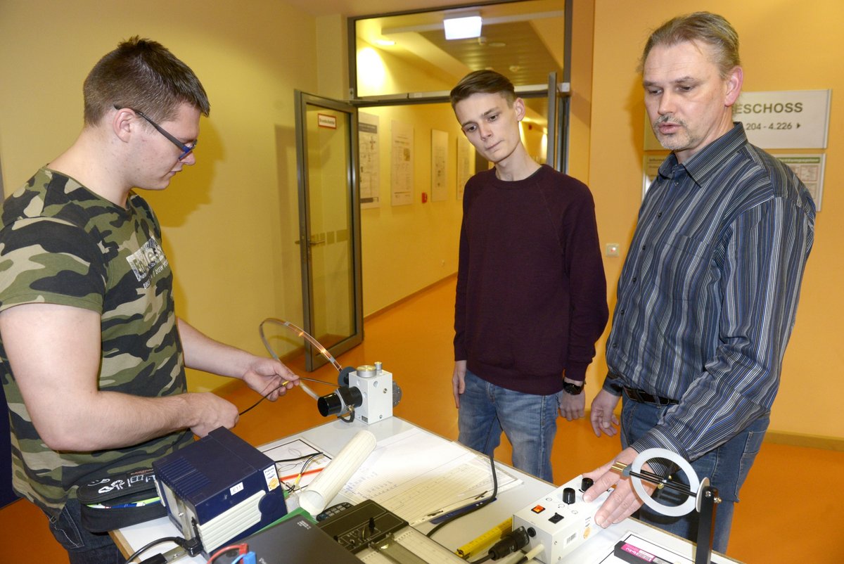 An einem Experimentiertisch stehend, führen Schüler einen Versuch zur Messung des Erdmagnetfeldes durch.