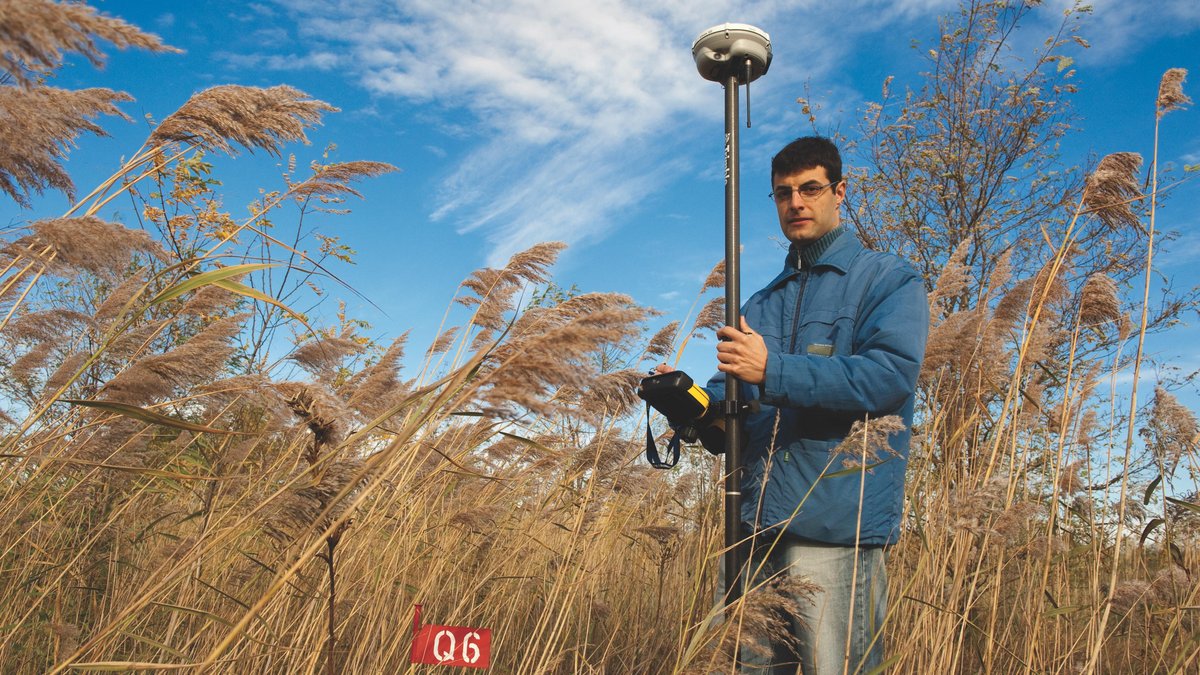 Ein Studierender steht mit einem Messgerät im künstlichen Wassereinzugsgebiet „Hühnerwasser“ – einem Forschungsprojekt der BTU