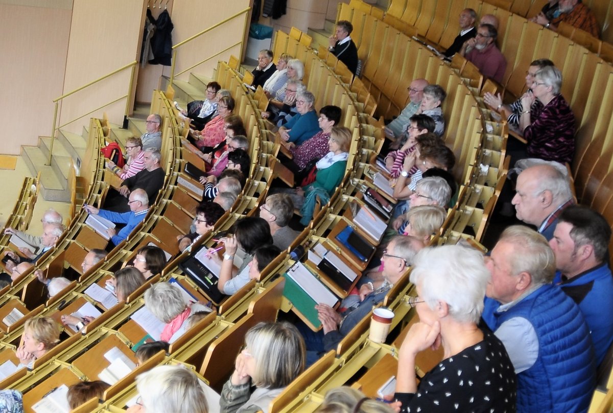 Seniorinnen und Senioren sitzen im Hörsaal und folgen einer Vorlesung.