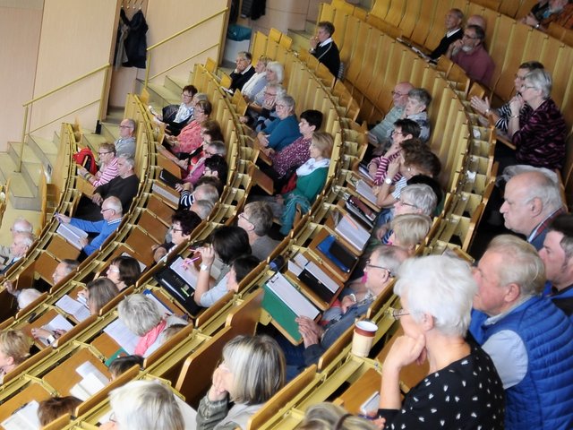 Seniorinnen und Senioren sitzen im Hörsaal und folgen einer Vorlesung.