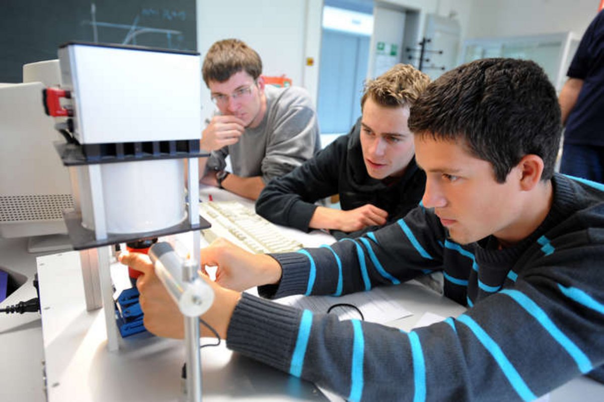 Schüler führen einen Versuch durch und stellen Geräte der Regelungstechnik ein.