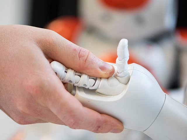 Humanroboter reicht einem Menschen die Hand