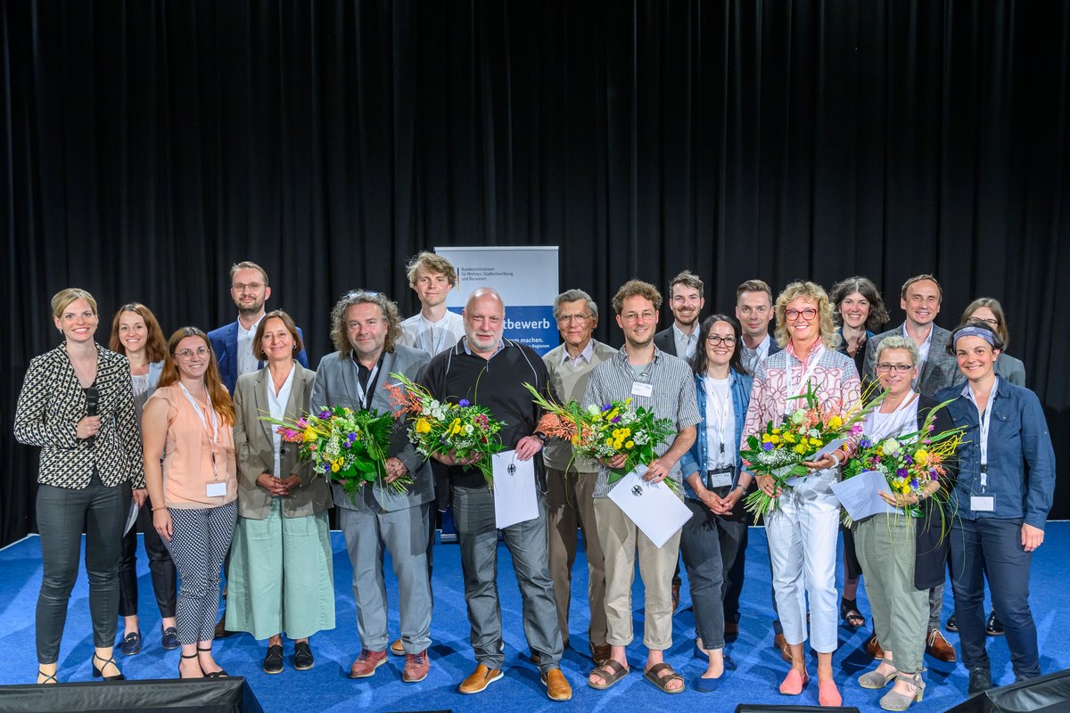 zweireihige Personengruppe, im Vordergrund die fünf Gewinner mit Blumensträußen