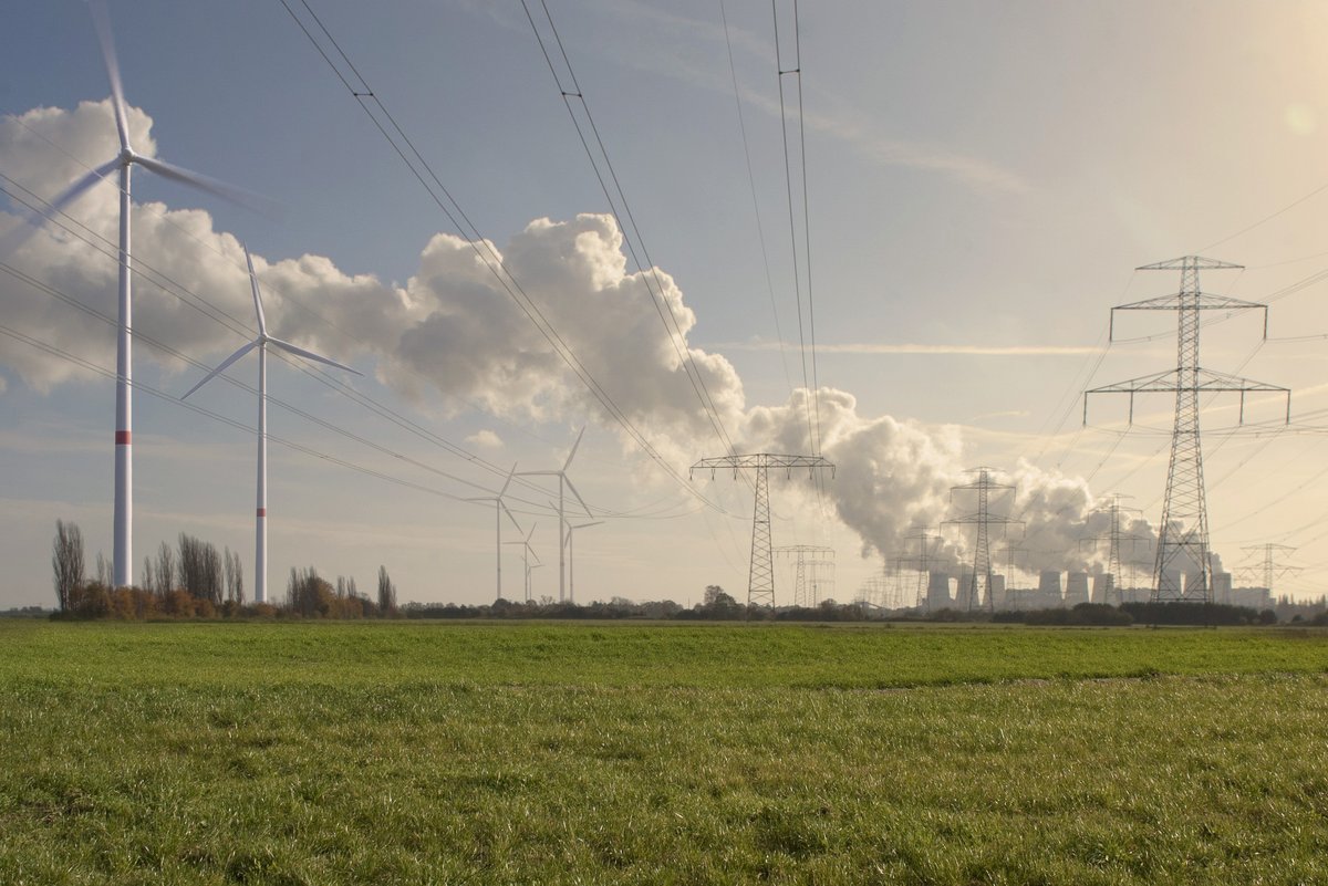 Windräder auf einem Feld, im Hintergrund das Kohle-Kraftwerk Jänschwalde.