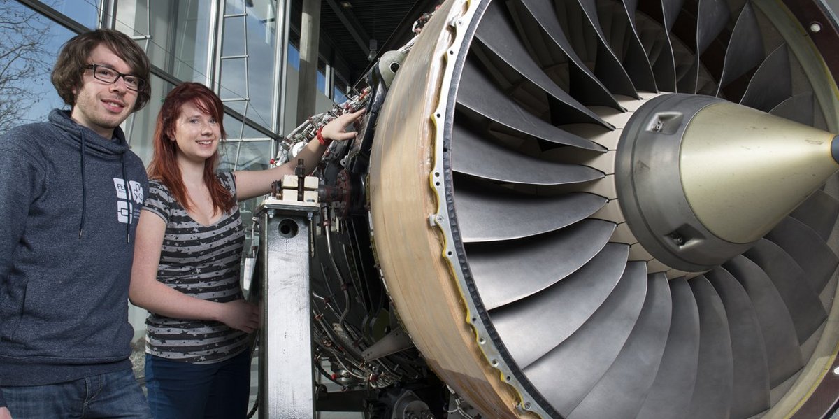 Students in the master's programme in mechanical engineering stand next to an aircraft turbine