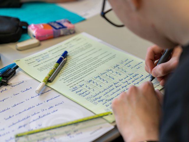 Jugendlicher löst schriflich Aufgaben. 