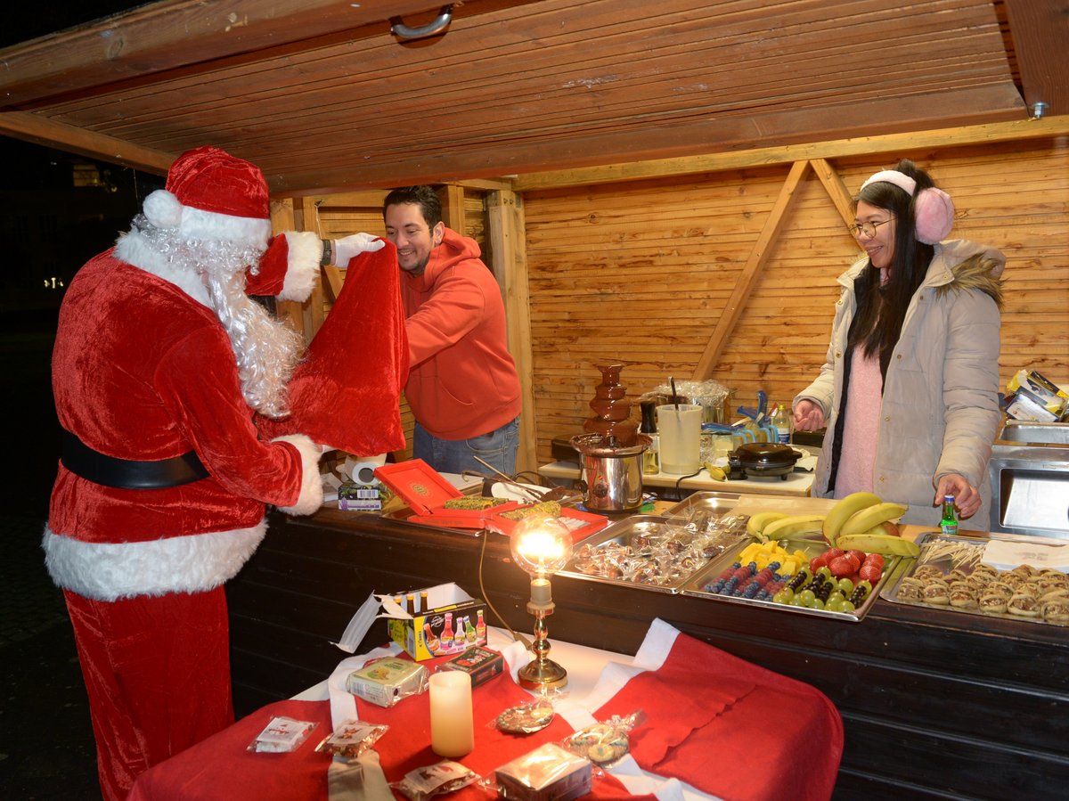 Der Weihnachtsmann verteilt Geschenke an einem Stand.