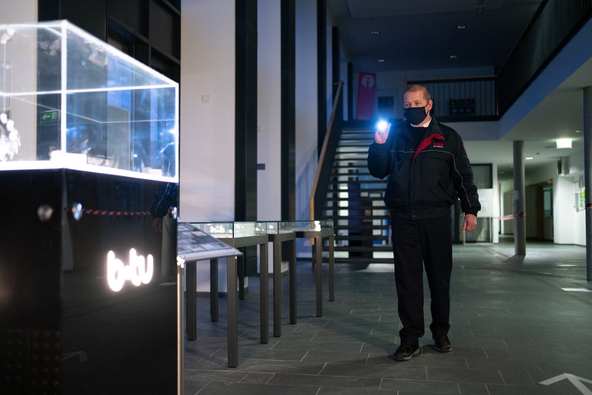 Securitas-Mitarbeiter patroulliert mit Taschenlampe im Foyer des Hauptgebäudes