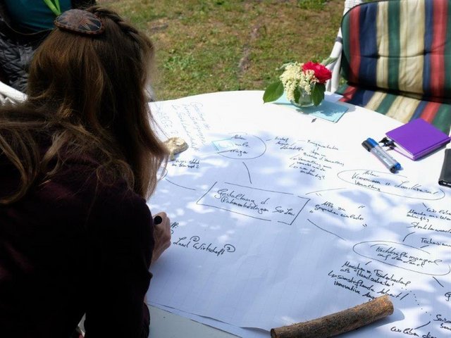 A woman works on a document spread out on a table in front of her.