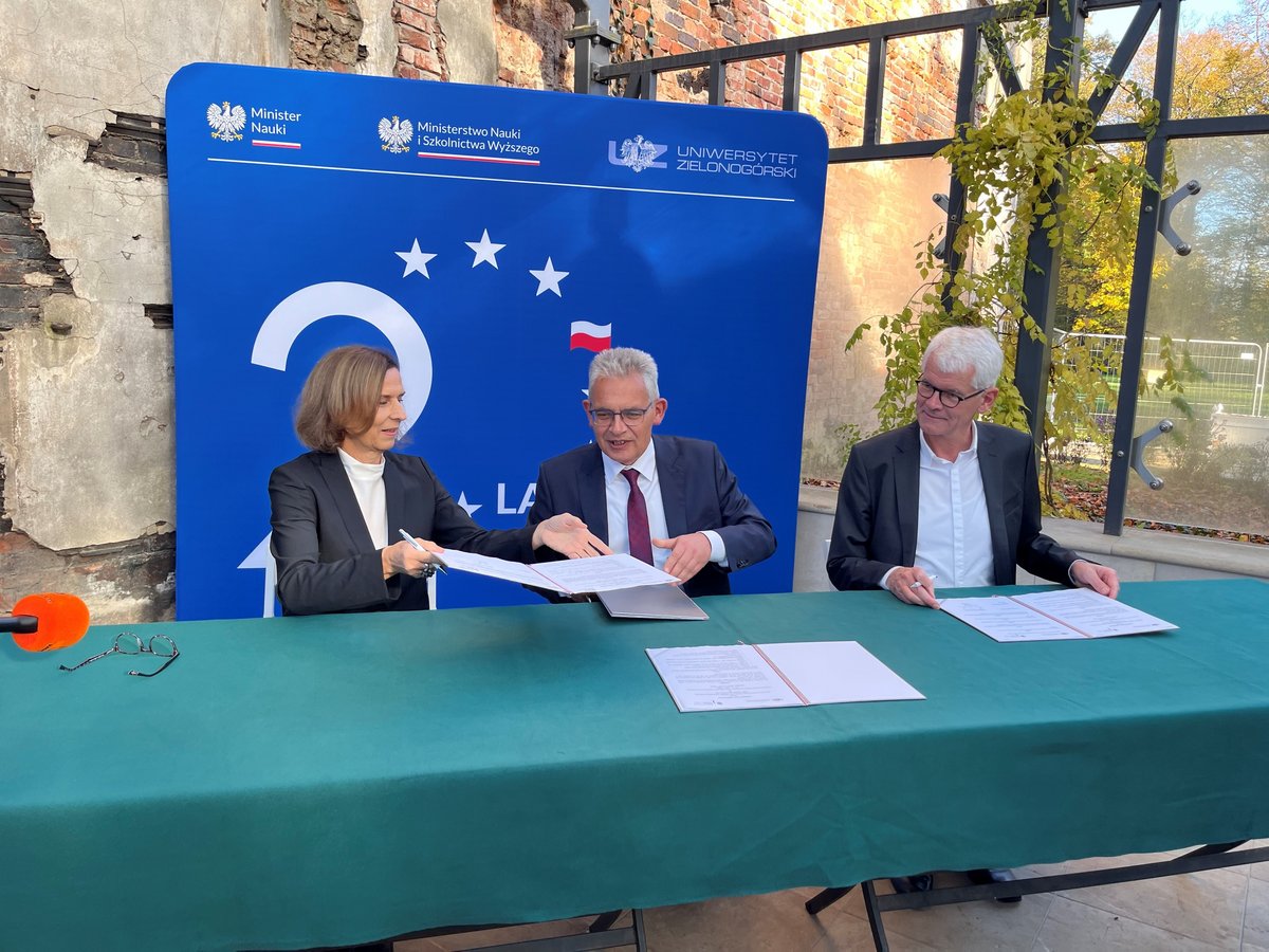 The partners sit at the table to sign