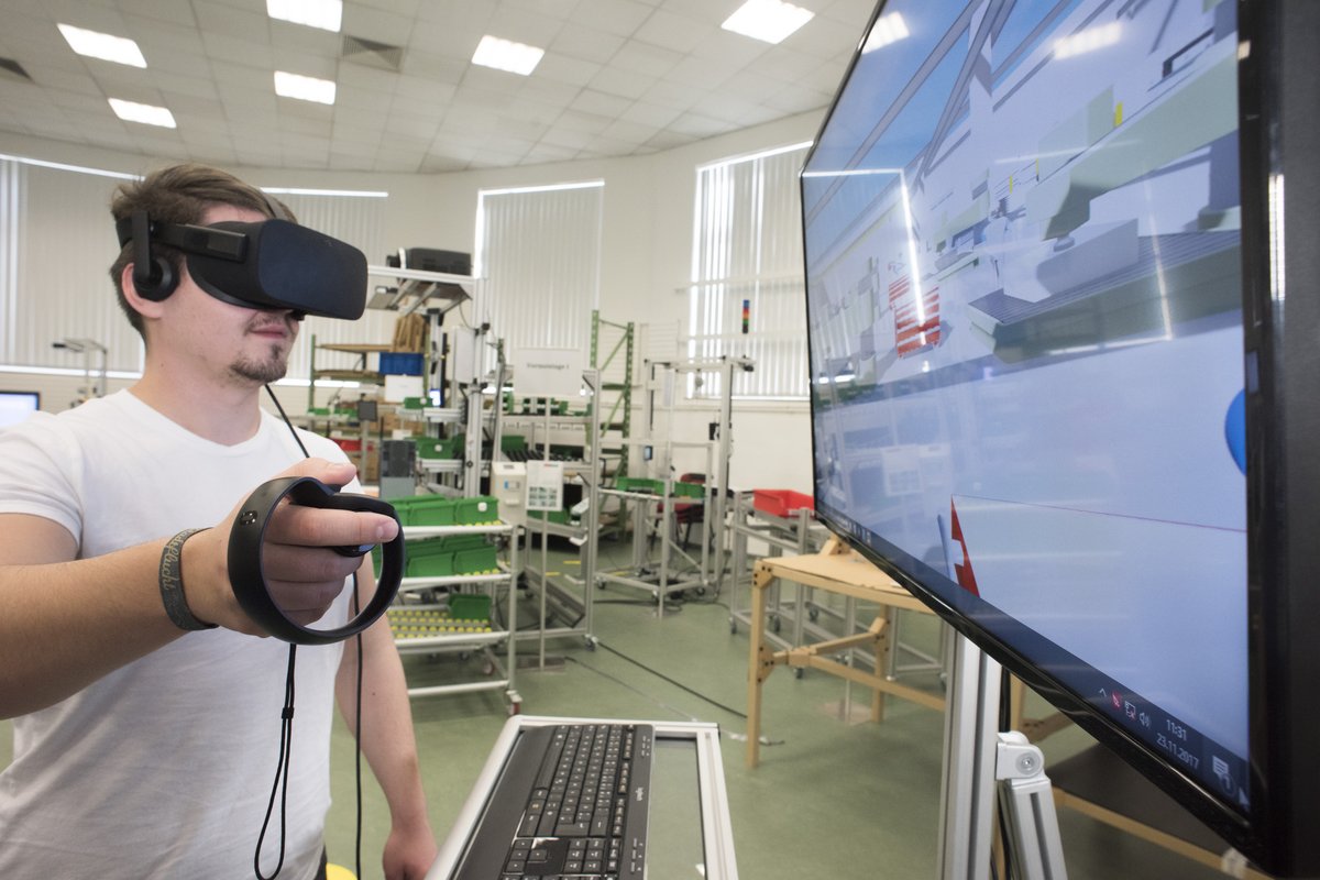 Studierender mit VR Brille bei der Begehung einer digitalen Fabrik.