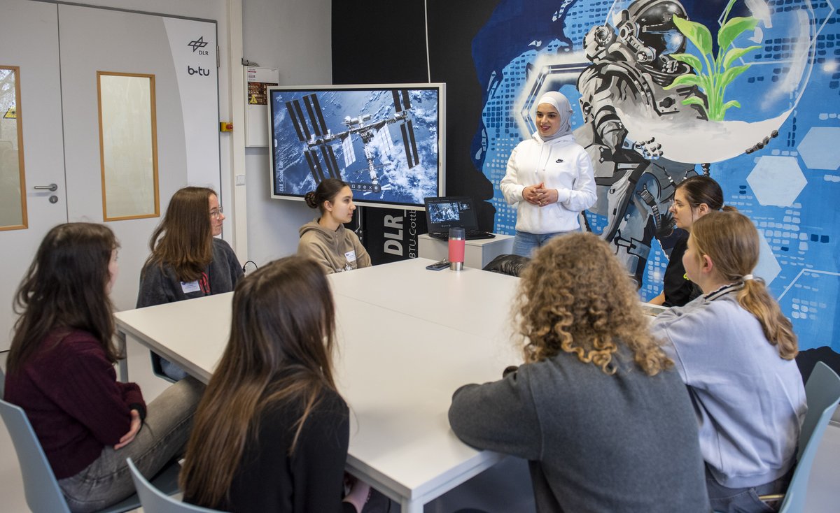 Schoolgirls, sitting at a table, follow a lecture.