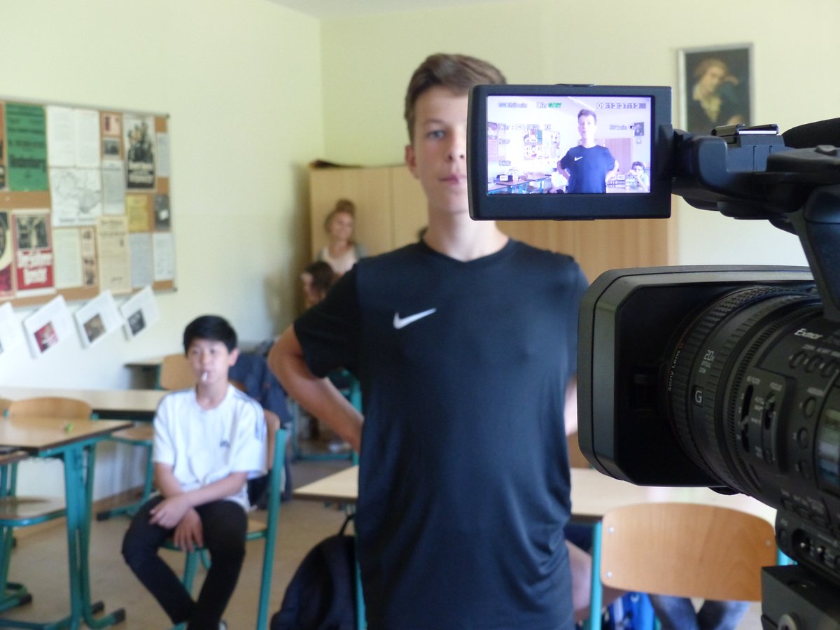 Schüler steht vor der Kamera, im Hintergrund ist der Klassenraum zu sehen