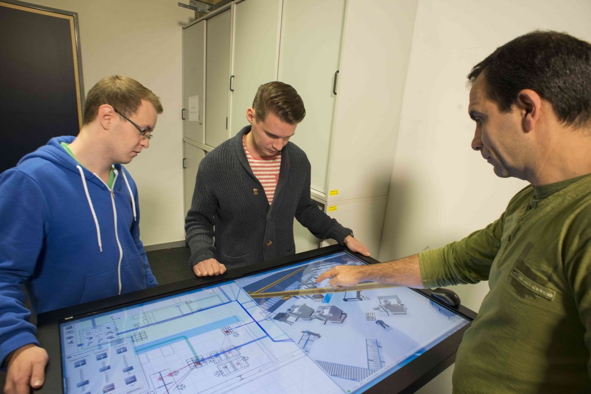 Studierende sowie Lehrkraft am Planungstisch der Fabrikplanung