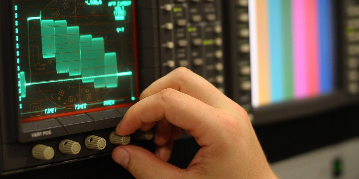 Hand to rotary knob of an oscilloscope graph