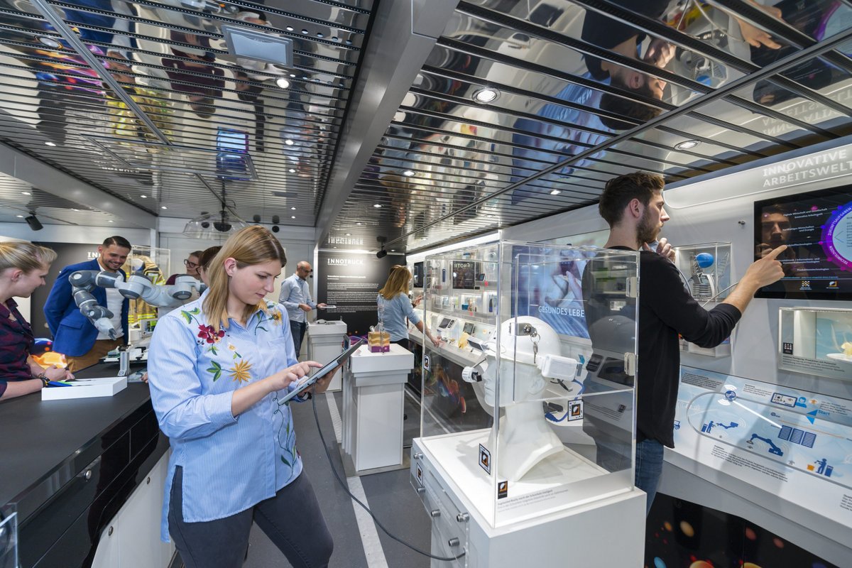 Besucherinnen und Besucher in formieren sich an den im  im InnoTruck ausgestelleten Exponaten.