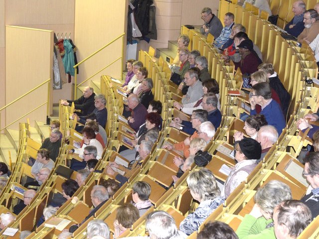 Senioren sitzen im Hörsaal und folgen einer Vorlesung.