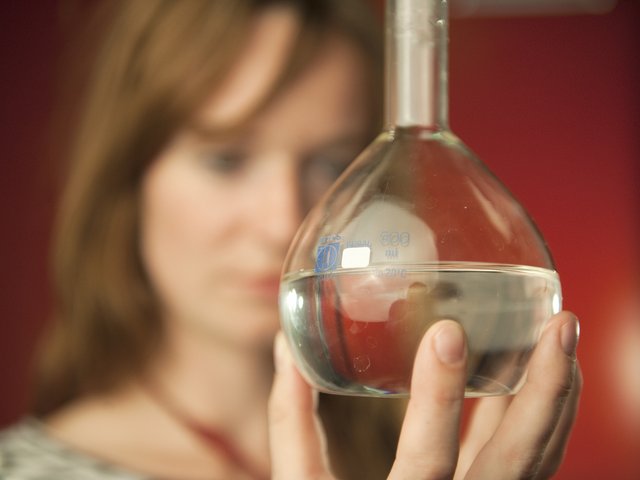 Das Gesicht einer Frau ist im Hintergrund, eine Hand hält einen Chemiekolben mit einer klaren Flüssigkeit, Synonym, Plakat mit Ausschreibungstext für den diesjährigen MINT-Preis der BTU