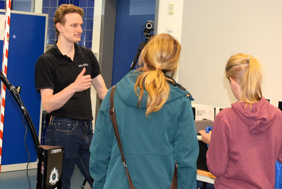 Ein Student gibt zwei Besucherinnen Erläuterungen im Laborgebäude der Therapiewissenschaften.