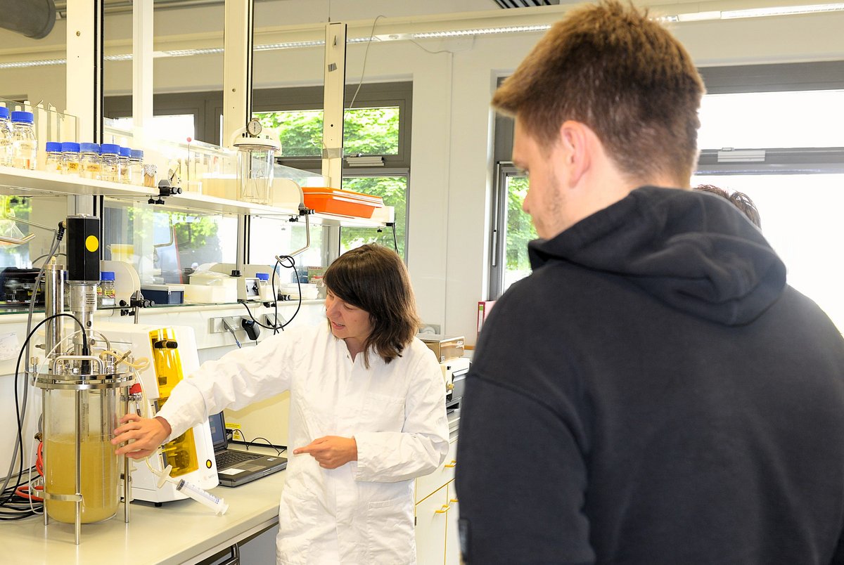 Eine Mitarbeiterin im Gespräch mit Besuchern in einem Biotechnologie-Labor.
