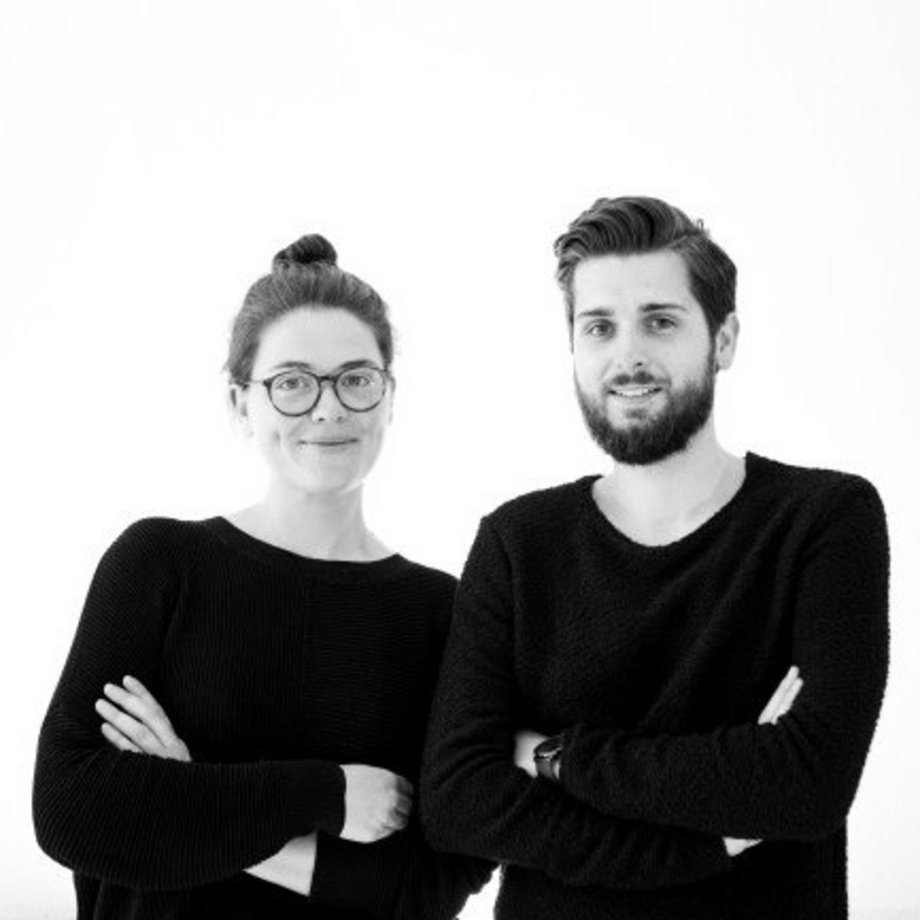 Architektur Absolventen Maria Constanze Hutter und Marc Timo Berg in schwarzer Kleidung vor weißem Hintergrund