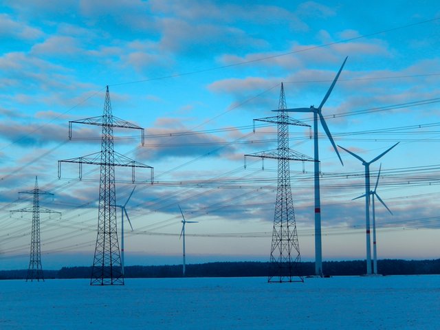 Strommasten und Windräder in der Winterlandschaft