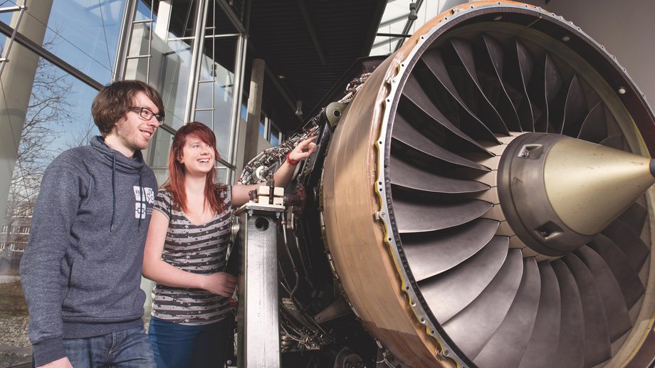 Zwei Studierende stehen neben einer Turbine