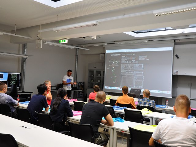 Studierende sitzen in einem Seminarraum und folgen einem Vorztrag.