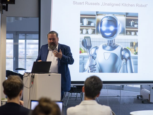 Prof. Zander am Rednerpult mit der Präsentation im Hintergrund