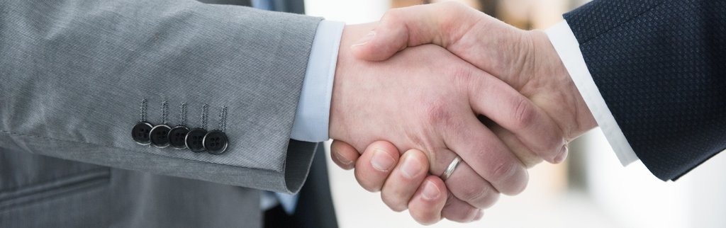 Händedruck Handschütteln von 2 Personen im Anzug, wobei nur die Hände und ein teil des Arms sichtbar sind.