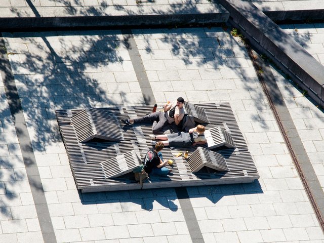 Drei Studierende sitzen auf einer Holzkonstrukton auf dem Campus. Foto: Ralf Scuster, BTU