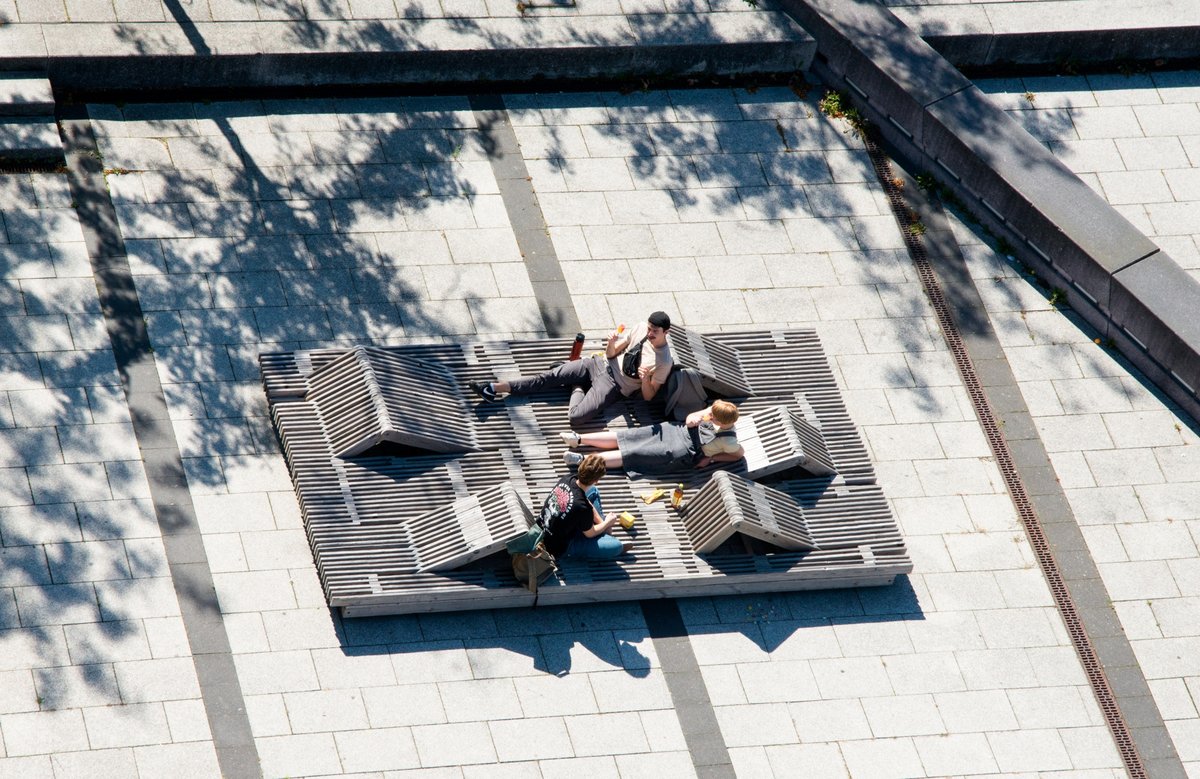 Drei Studierende sitzen auf einer Holzkonstrukton auf dem Campus. Foto: Ralf Scuster, BTU