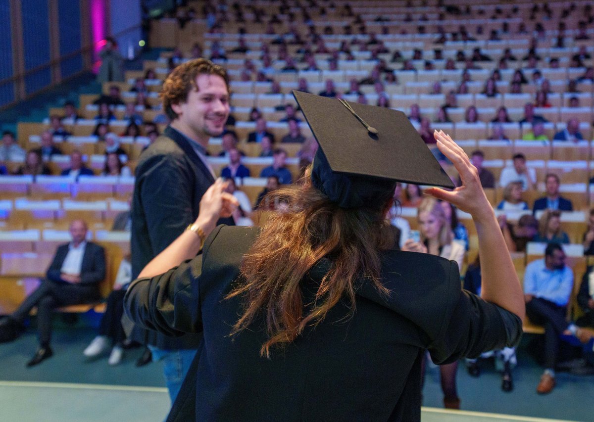 Junge Frau mit Doktorhut vor dem Auditorium