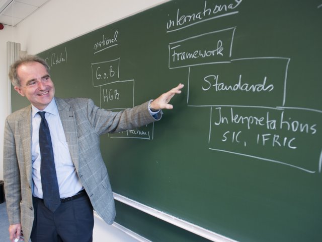 Ein Professor vor einer Tafel während einer BWL-Vorlesung
