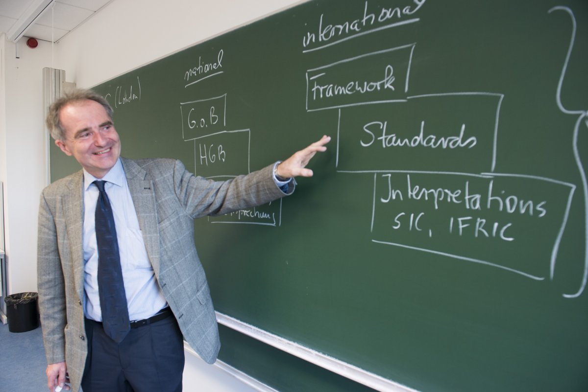 Ein Professor vor einer Tafel während einer BWL-Vorlesung
