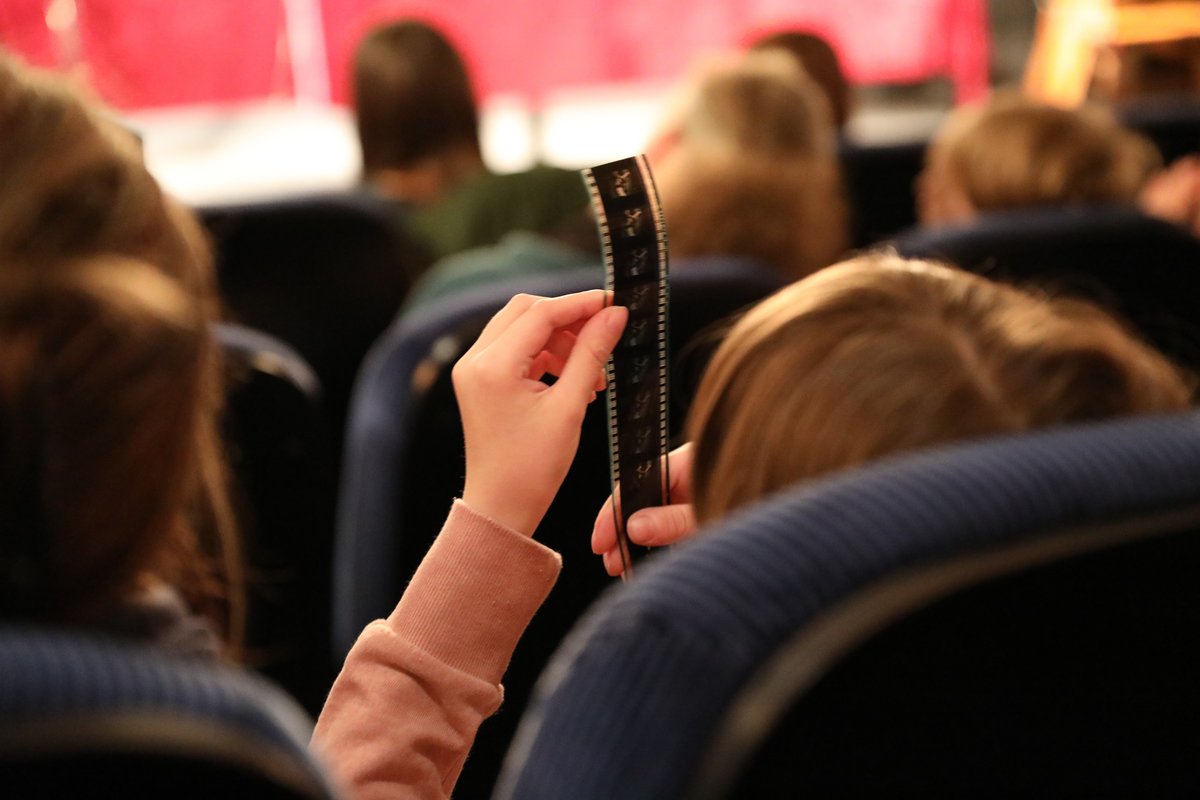 Kinder sitzen im Kinosaal. Nahaufnahme Kind von hinten, dass sich einen Negativstreifen anschaut